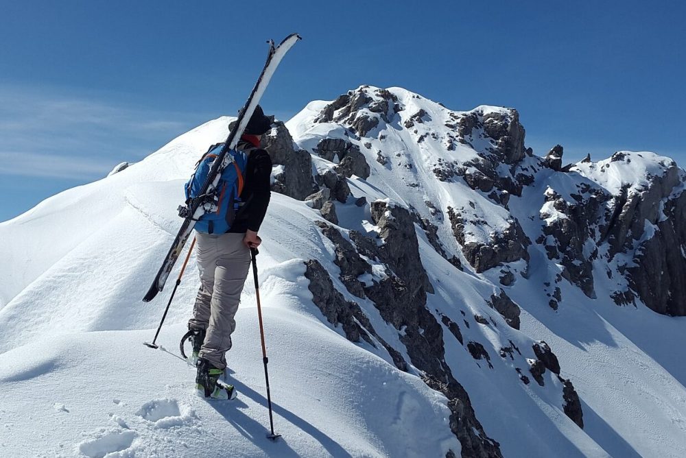 Beispielbild eines Tourenski- Sportlers auf dem Weg zum Berggipfel.